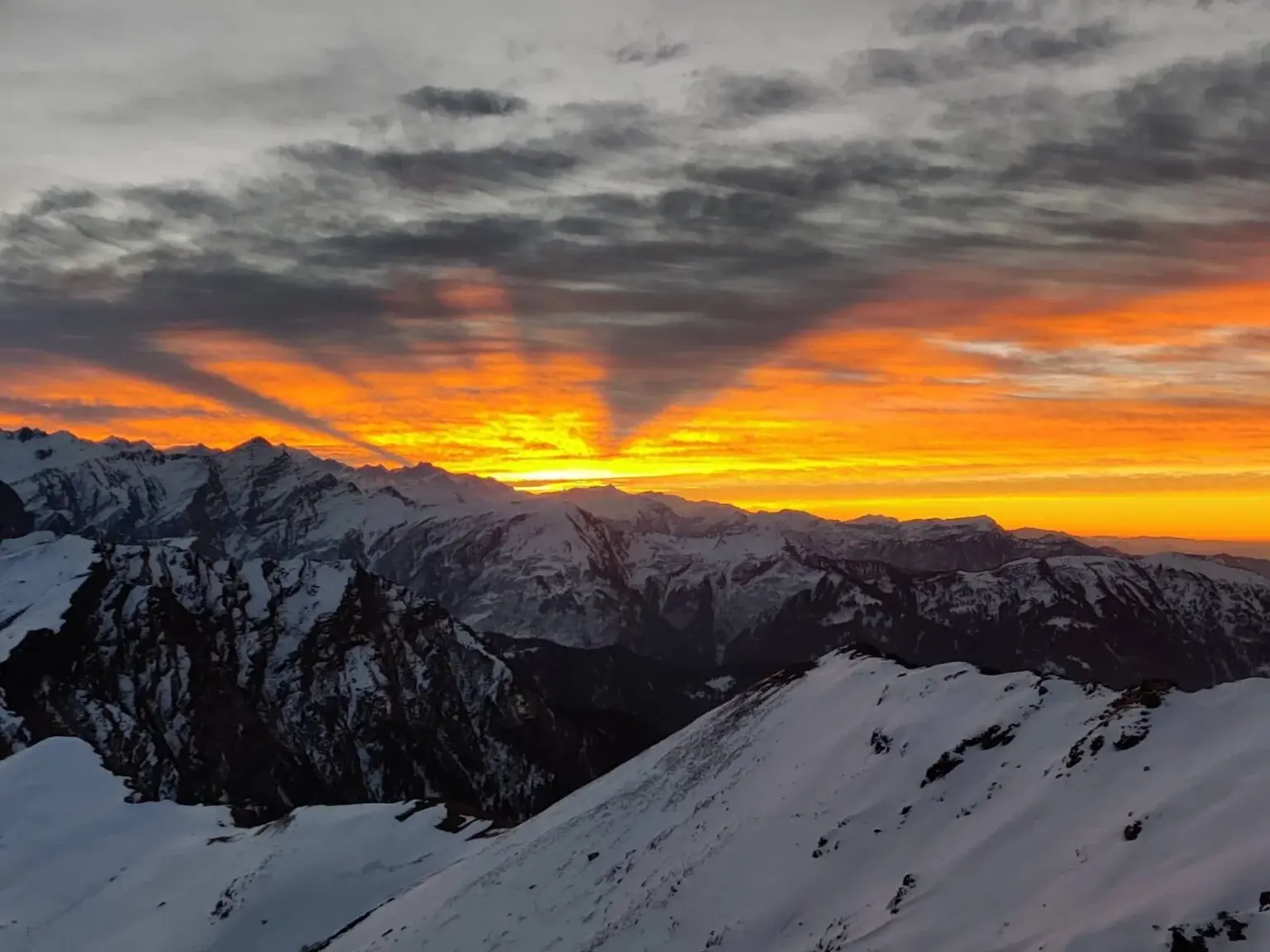 Trekker reaching the Kedarkantha summit with panoramic views of the Himalayan peaks.