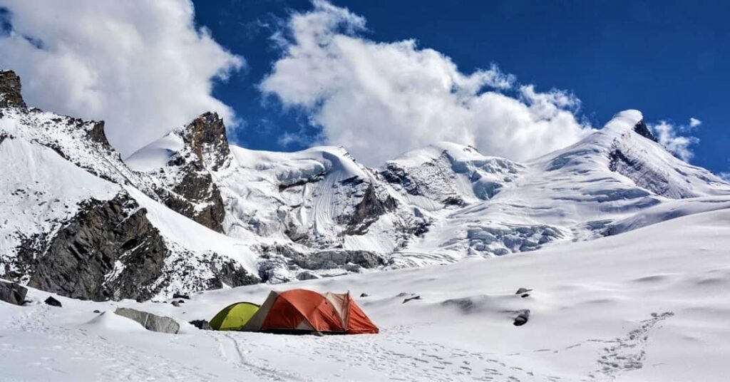 Tent set up on Dhumdhar Kandi trek, one of India’s most difficult trails, surrounded by clear white snow under a bright blue sky.