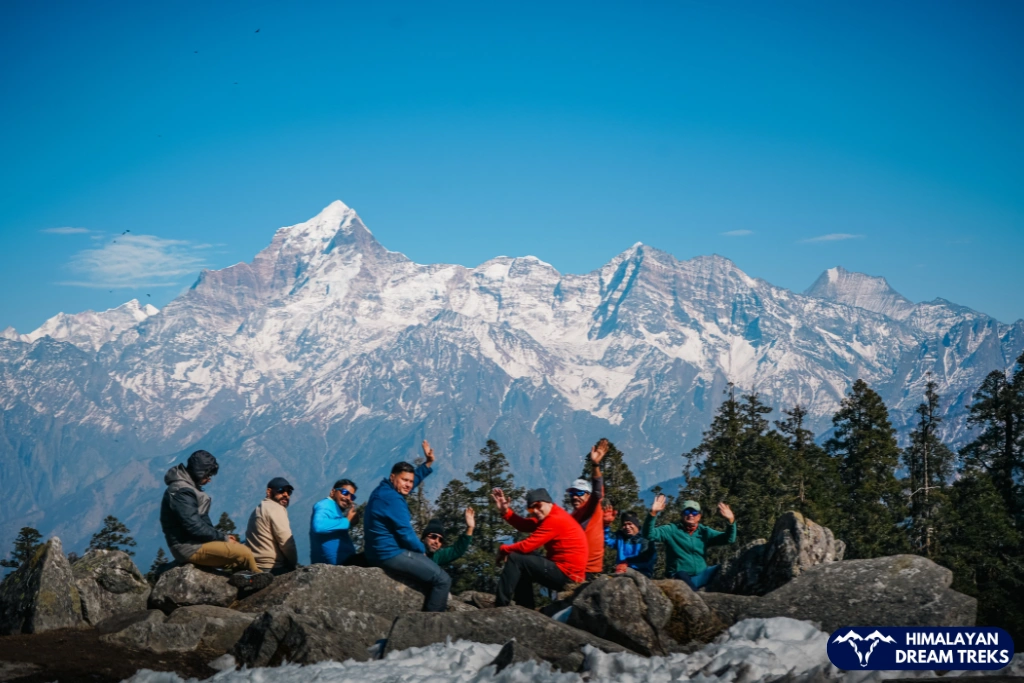 Group of trekkers relaxing on rocks with the snow-covered Himalayan peaks during the lord curzon trail