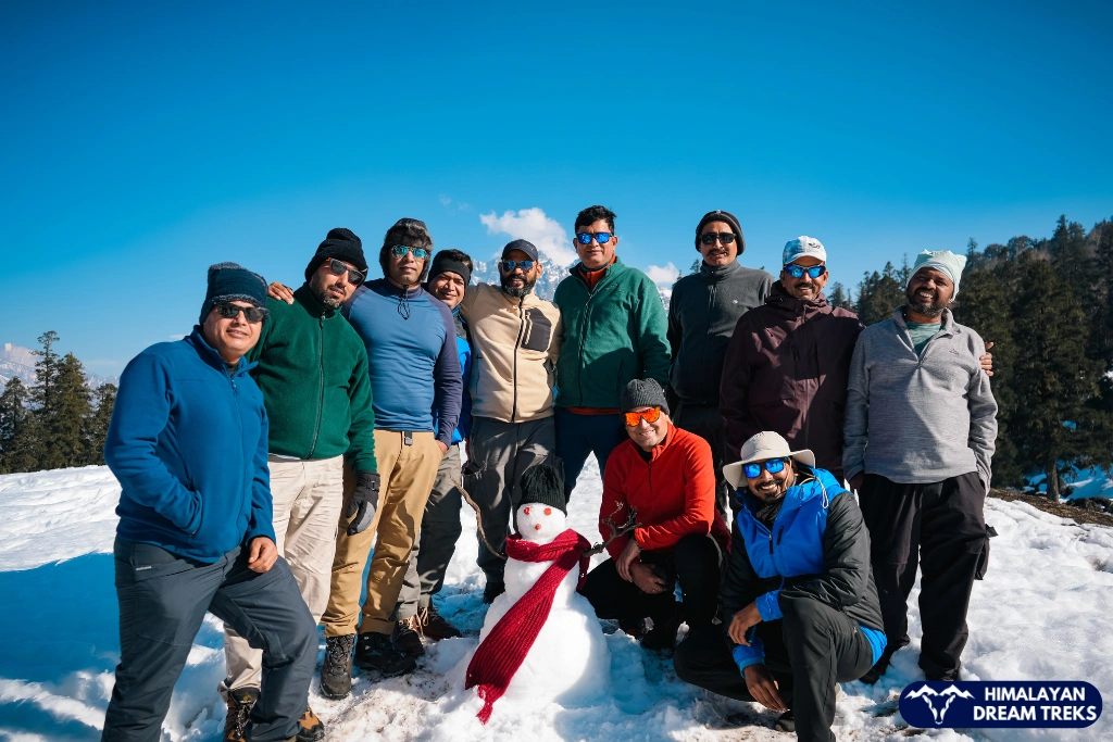 Trekkers posing together on the snow during the Kuari Pass winter trek in Uttarakhand
