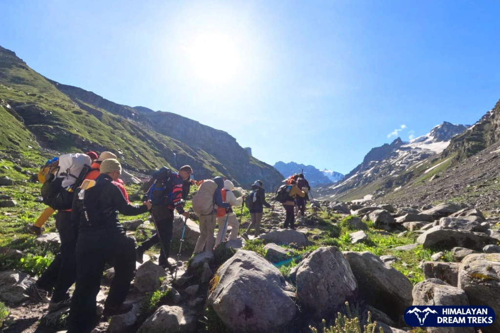 Trekkers walking on rocky trail with Himalayan views