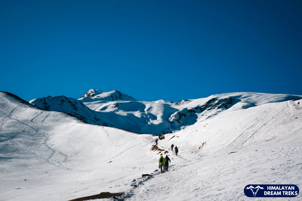 Trekkers walking through deep snow during the Kuari Pass Trek in Uttarakhand