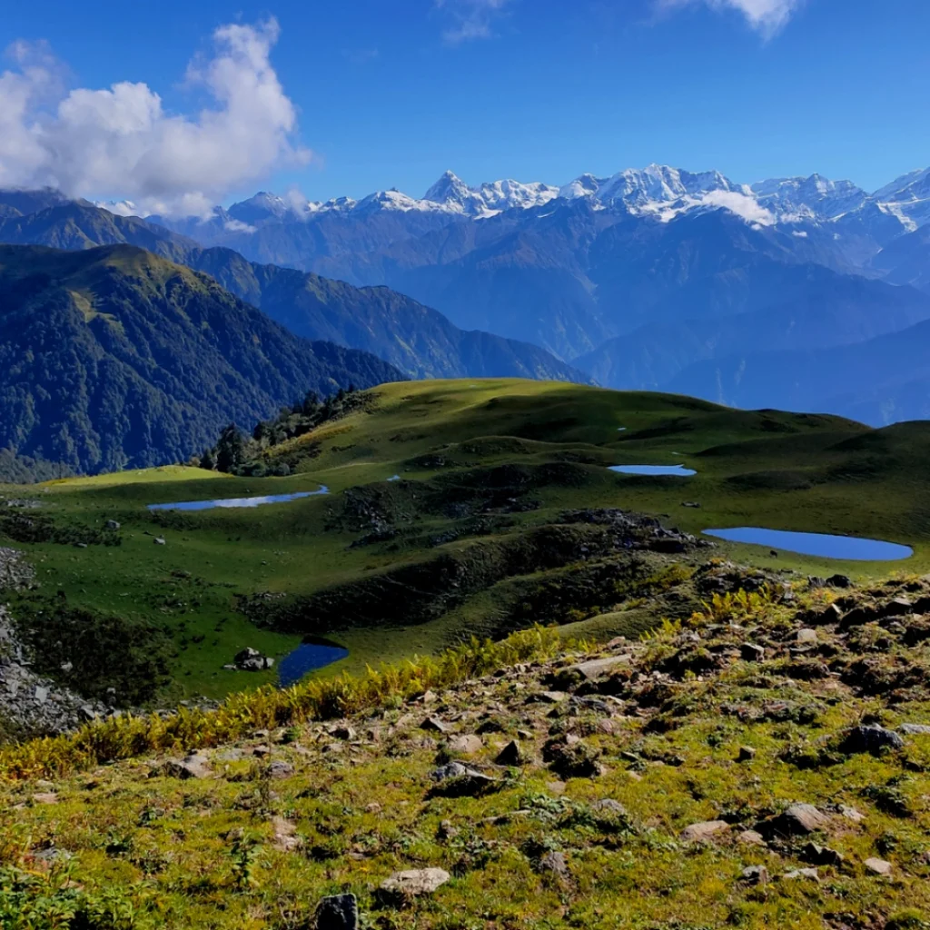 Scenic landscape of Gidara Bugyal with rolling grasslands and distant snow-capped mountains