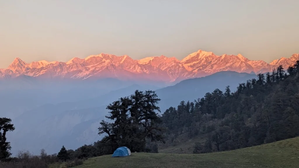 Sunset on a Himalayan peak with a campsite at Dayara Bugyal